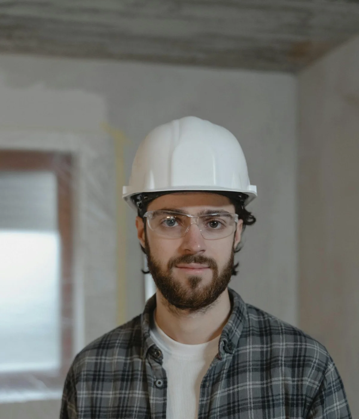 Engenheiro responsável pela obra, com capacete e óculos de proteção, em apartamento em reforma